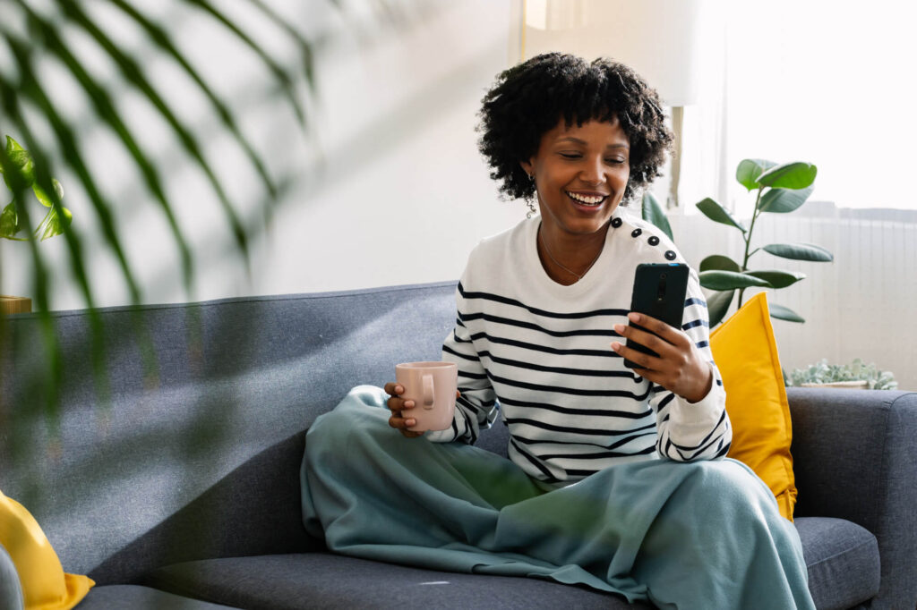 Woman enjoying a cup of coffee on her couch in her bright apartment living room